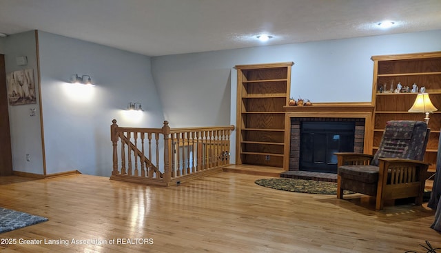 sitting room featuring a fireplace, an upstairs landing, and wood finished floors