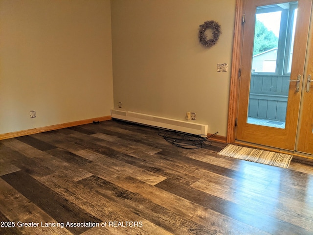 spare room featuring baseboard heating, dark wood-style flooring, and baseboards
