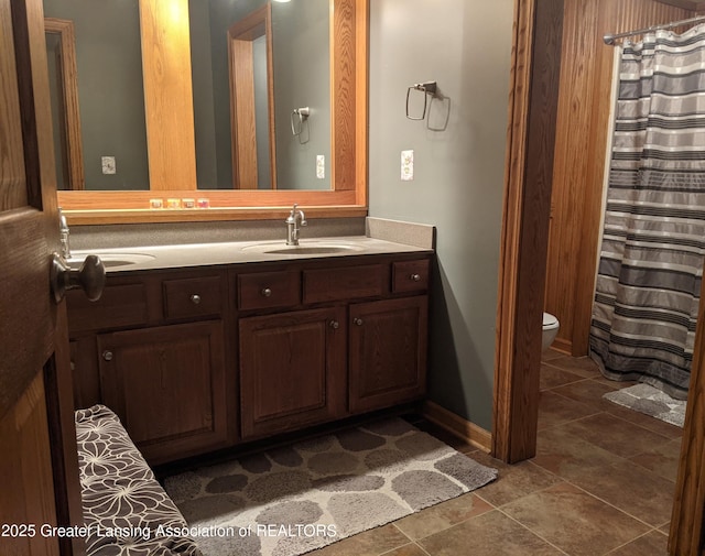 bathroom with toilet, a shower with shower curtain, vanity, and baseboards