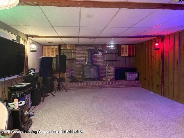 11100 Anderson Rd, Litchfield, MI 49252 - living room with a wood stove, a paneled ceiling, wood walls, and carpet floors