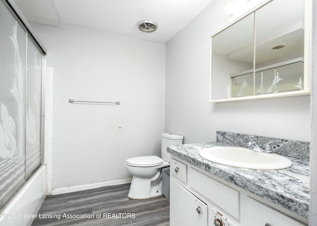 5026 Delray Dr, Lansing, MI 48910 - full bath with visible vents, toilet, enclosed tub / shower combo, vanity, and wood finished floors