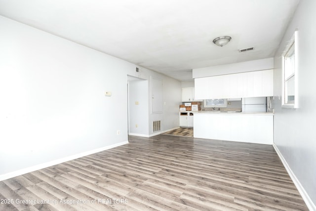 5026 Delray Dr, Lansing, MI 48910 - unfurnished living room featuring visible vents, baseboards, and wood finished floors