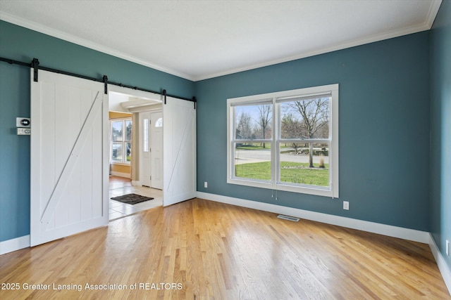 3430 Hawthorne Woods Pkwy, Dewitt, MI 48820 - unfurnished room with a barn door, visible vents, baseboards, and light wood-type flooring
