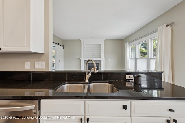 3430 Hawthorne Woods Pkwy, Dewitt, MI 48820 - kitchen with white cabinets, a barn door, dark stone counters, dishwasher, and a sink