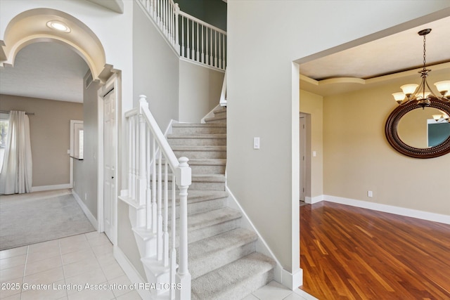 3430 Hawthorne Woods Pkwy, Dewitt, MI 48820 - stairs featuring tile patterned floors, a notable chandelier, baseboards, and carpet floors