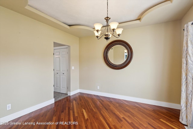 3430 Hawthorne Woods Pkwy, Dewitt, MI 48820 - empty room featuring a tray ceiling, baseboards, a notable chandelier, and wood finished floors