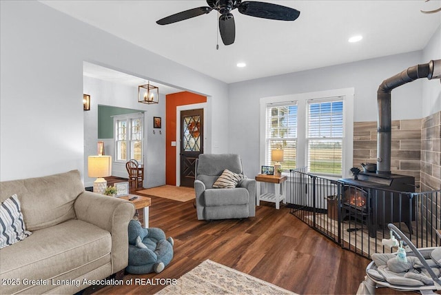 living area featuring wood finished floors, ceiling fan, recessed lighting, and a wood stove