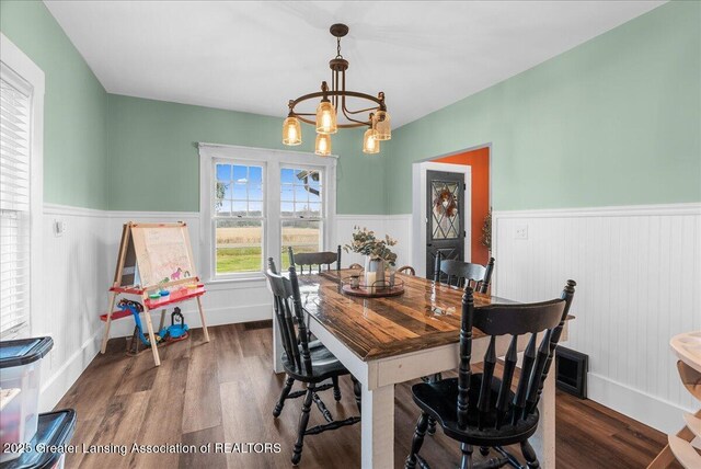 dining room featuring wood finished floors, a notable chandelier, and wainscoting