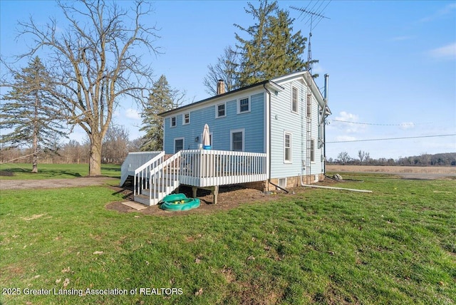 view of front facade featuring a chimney, a front yard, and a deck
