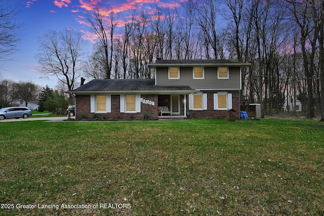 traditional home featuring a yard, a chimney, covered porch, and brick siding