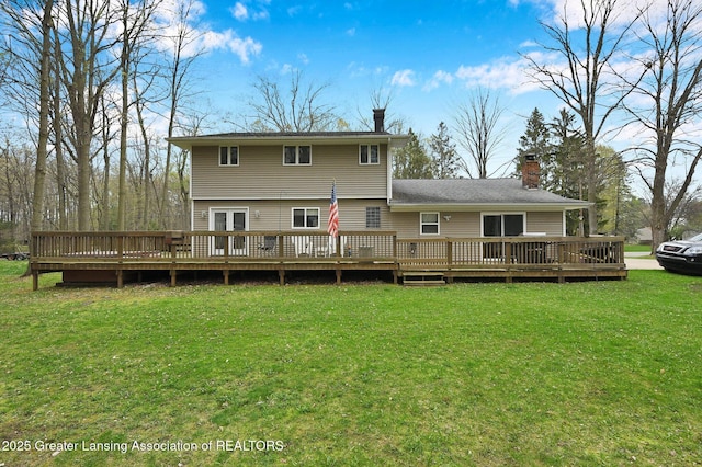 rear view of house with a wooden deck, a yard, and a chimney