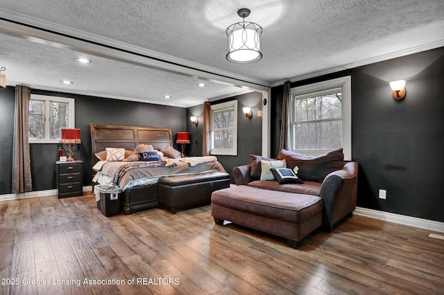 bedroom featuring crown molding, a textured ceiling, wood finished floors, and baseboards