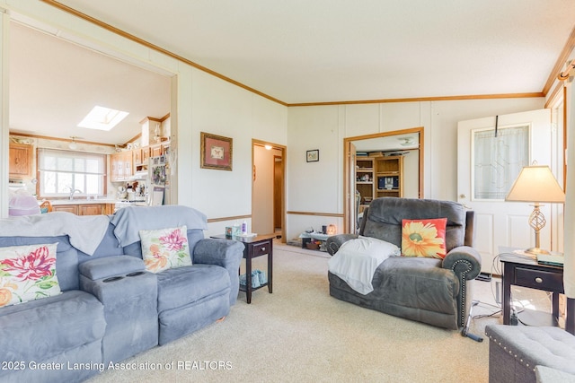 living area featuring a decorative wall, a skylight, ornamental molding, and carpet floors