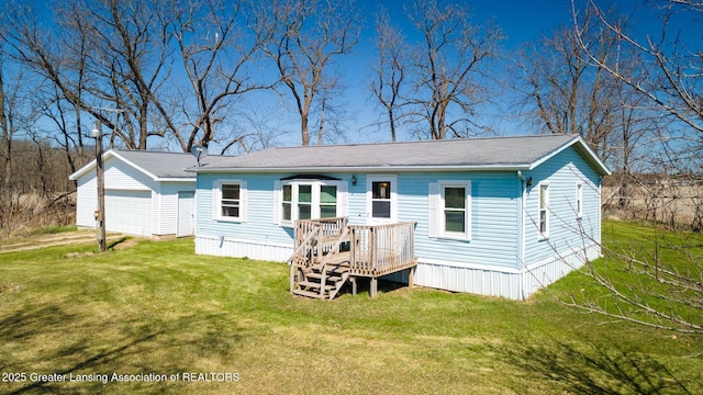 back of house with a detached garage, a deck, and a lawn