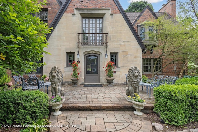 728 Audubon Rd, East Lansing, MI 48823 - view of exterior entry with a balcony, a patio, and stone siding