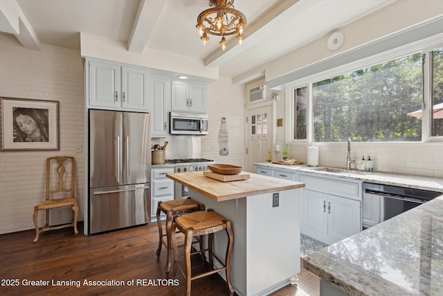 728 Audubon Rd, East Lansing, MI 48823 - kitchen featuring stainless steel appliances, butcher block counters, beam ceiling, backsplash, and dark wood-type flooring