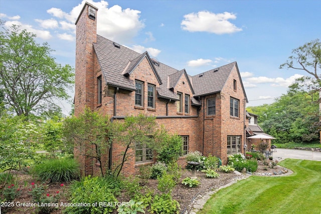 728 Audubon Rd, East Lansing, MI 48823 - view of property exterior featuring a chimney, brick siding, a lawn, and a high end roof