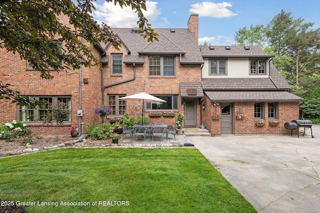 728 Audubon Rd, East Lansing, MI 48823 - view of front of house featuring a chimney, a front yard, brick siding, and a patio area