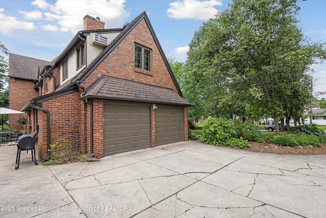728 Audubon Rd, East Lansing, MI 48823 - view of home's exterior featuring a chimney, brick siding, a garage, and driveway