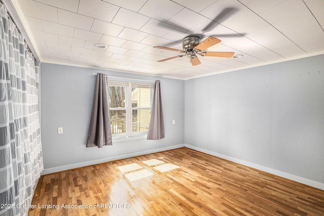 unfurnished room with ceiling fan, baseboards, crown molding, and wood finished floors