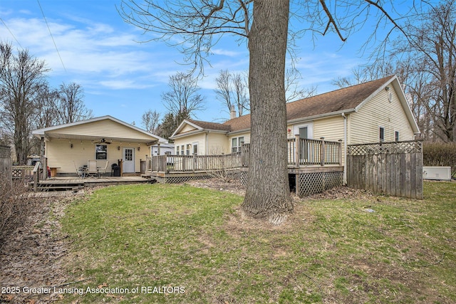 rear view of property with a yard, a wooden deck, and a ceiling fan