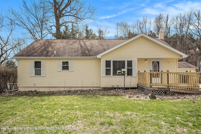 view of front of house featuring a front yard, a wooden deck, and a shingled roof