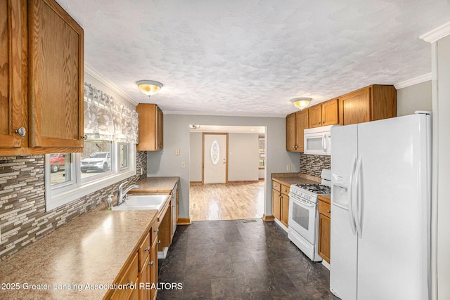 kitchen with a sink, ornamental molding, and white appliances