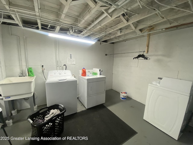 laundry room with washing machine and clothes dryer, a sink, and laundry area