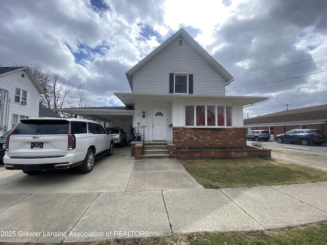 view of front facade featuring a carport, driveway, brick siding, and board and batten siding