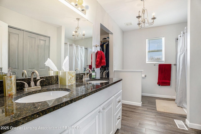 full bath with a chandelier, wood finished floors, visible vents, and a sink