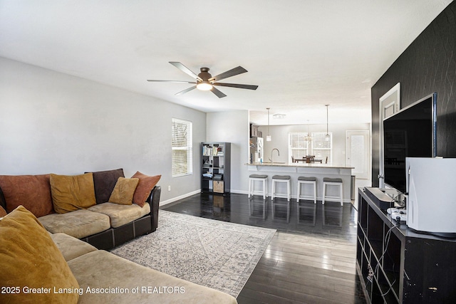 living room with dark wood finished floors, baseboards, and a ceiling fan