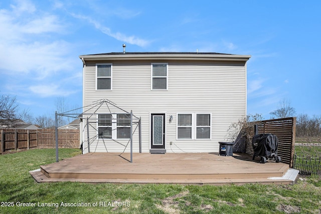rear view of property featuring a wooden deck, a yard, and a fenced backyard