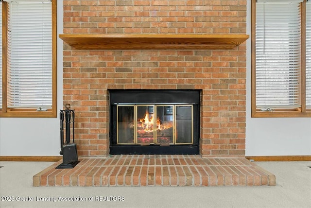 room details featuring baseboards and a brick fireplace