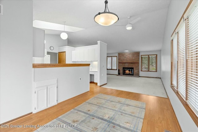 unfurnished living room featuring lofted ceiling, visible vents, a fireplace, and light wood-type flooring