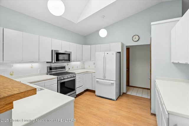 kitchen with high vaulted ceiling, appliances with stainless steel finishes, light wood-style flooring, and light countertops
