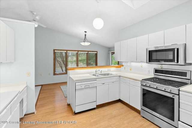 kitchen featuring white cabinets, vaulted ceiling, appliances with stainless steel finishes, and a sink