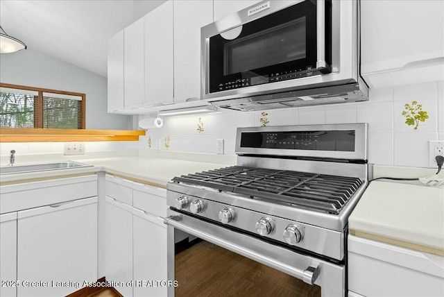 kitchen featuring decorative backsplash, light countertops, white cabinetry, and appliances with stainless steel finishes