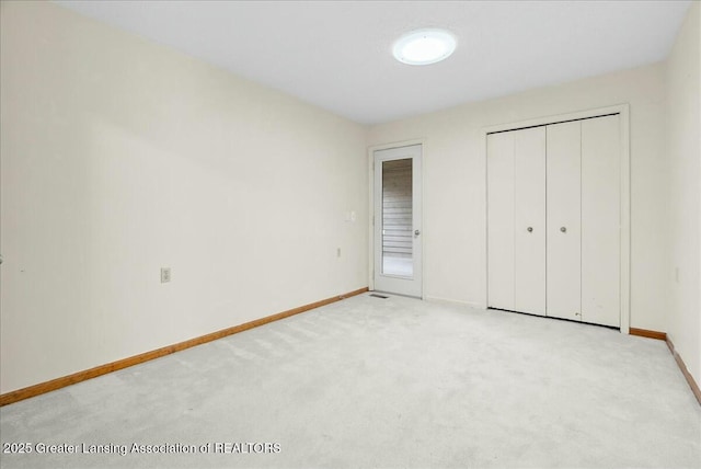unfurnished bedroom with light carpet, baseboards, and a closet