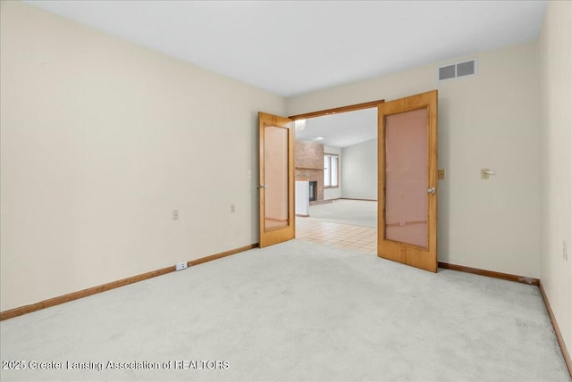 empty room featuring visible vents, baseboards, and light carpet
