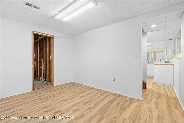 spare room with visible vents, light wood-style floors, and a paneled ceiling