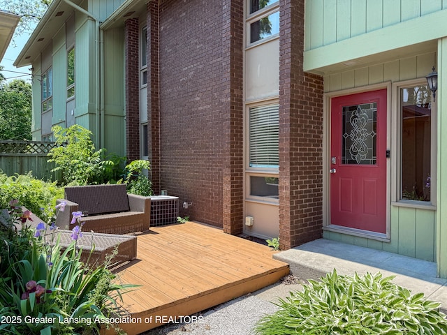 515 N Putnam St Unit B, Williamston, MI 48895 - view of exterior entry featuring a wooden deck, brick siding, and central AC