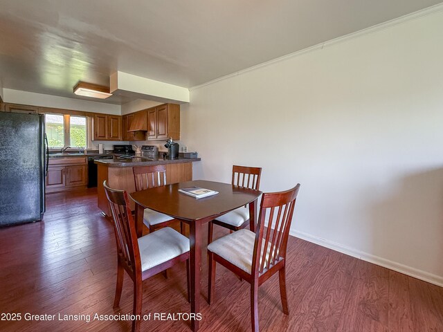 515 N Putnam St Unit B, Williamston, MI 48895 - dining space with dark wood-type flooring, baseboards, and crown molding