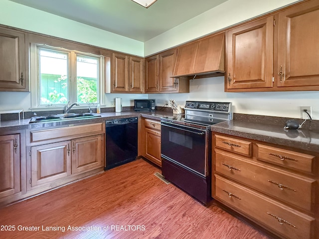 515 N Putnam St Unit B, Williamston, MI 48895 - kitchen with black appliances, premium range hood, a sink, and dark countertops