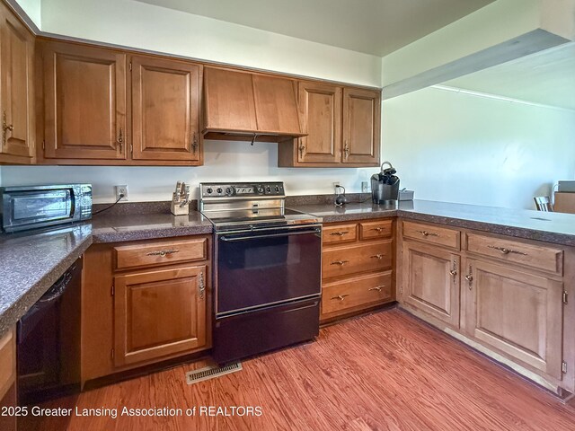 515 N Putnam St Unit B, Williamston, MI 48895 - kitchen featuring black appliances, custom exhaust hood, light wood finished floors, and dark countertops