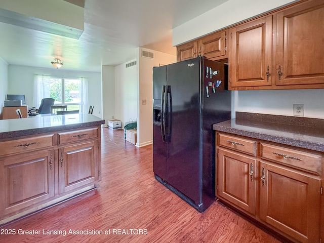 515 N Putnam St Unit B, Williamston, MI 48895 - kitchen with black refrigerator with ice dispenser, light wood-style floors, dark countertops, and brown cabinets
