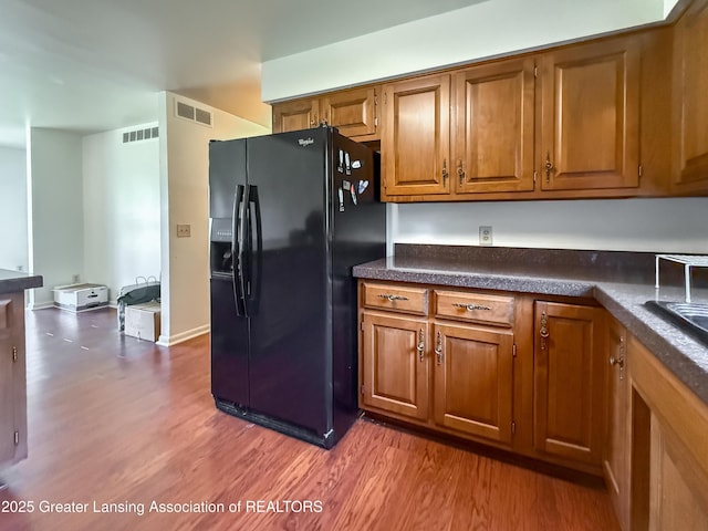 515 N Putnam St Unit B, Williamston, MI 48895 - kitchen with black fridge, brown cabinets, wood finished floors, and dark countertops