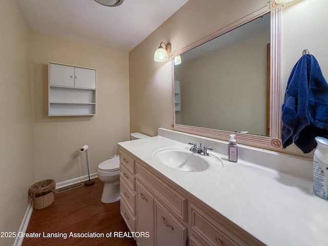 515 N Putnam St Unit B, Williamston, MI 48895 - bathroom featuring toilet, vanity, wood finished floors, and baseboards