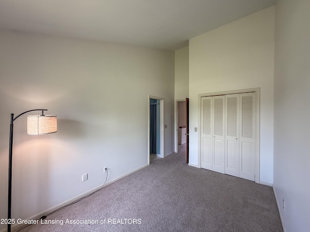 515 N Putnam St Unit B, Williamston, MI 48895 - unfurnished bedroom featuring carpet, baseboards, a towering ceiling, and a closet