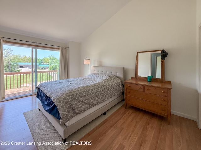 515 N Putnam St Unit B, Williamston, MI 48895 - bedroom featuring vaulted ceiling, access to exterior, light wood-type flooring, and baseboards