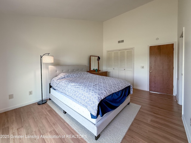 515 N Putnam St Unit B, Williamston, MI 48895 - bedroom featuring baseboards, high vaulted ceiling, wood finished floors, and a closet